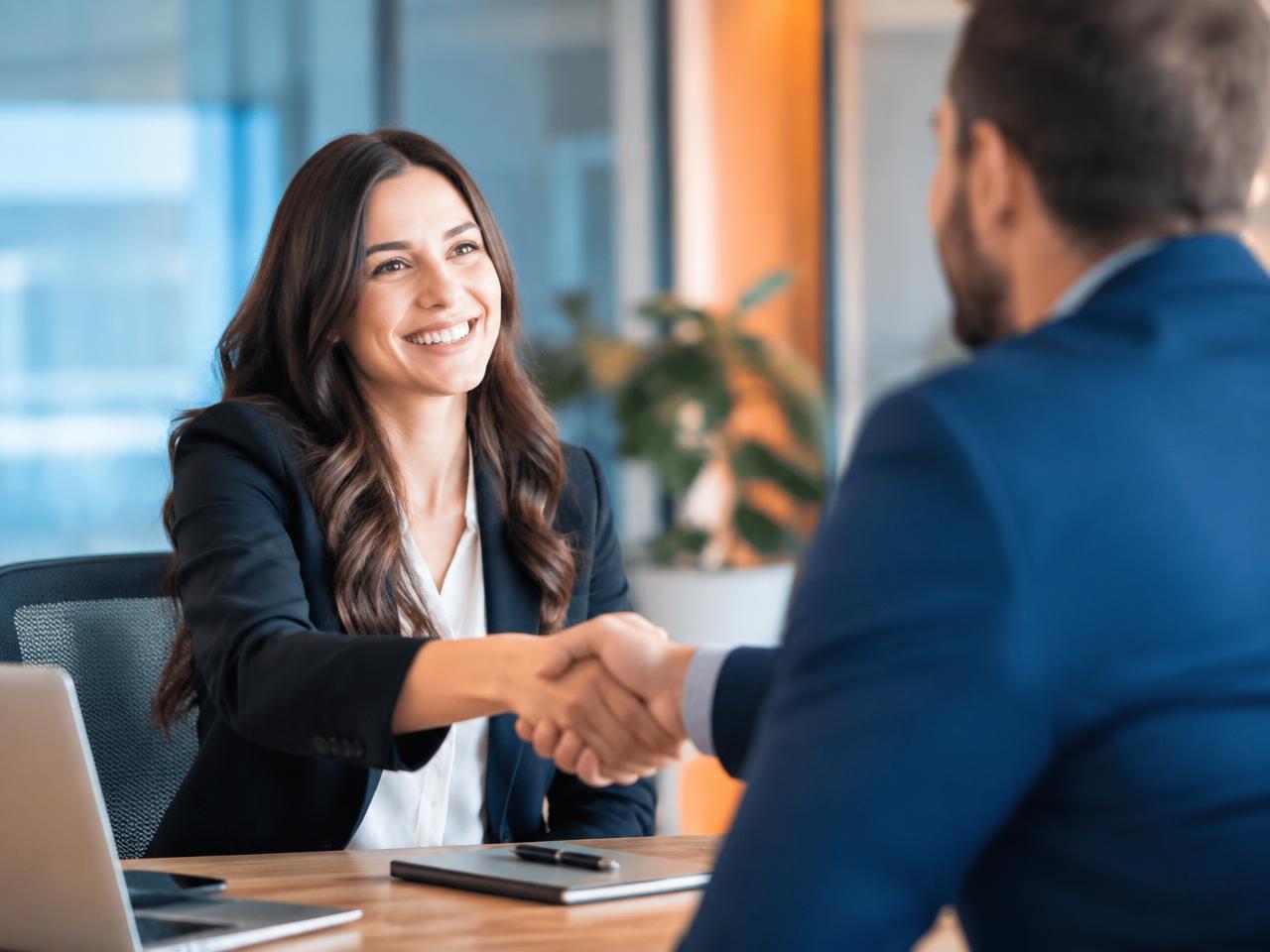 Recruiter welcoming a candidate with a handshake in a modern office